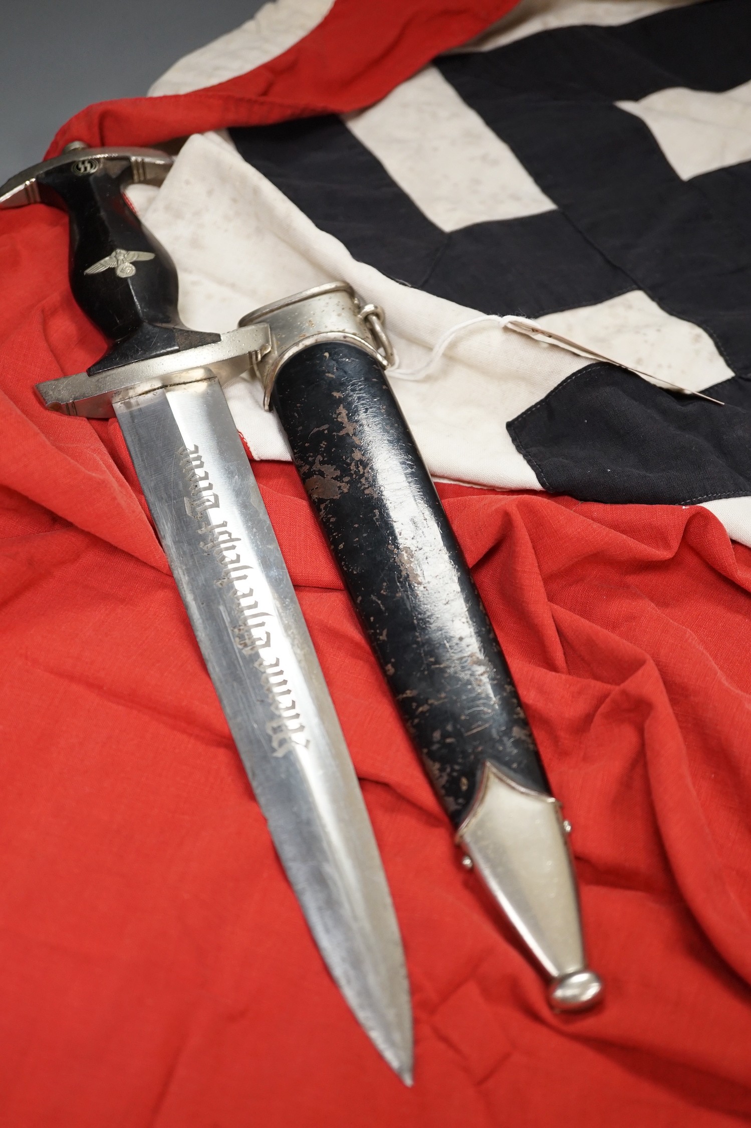 A Third Reich SS dagger, German steel helmet and a Nazi flag